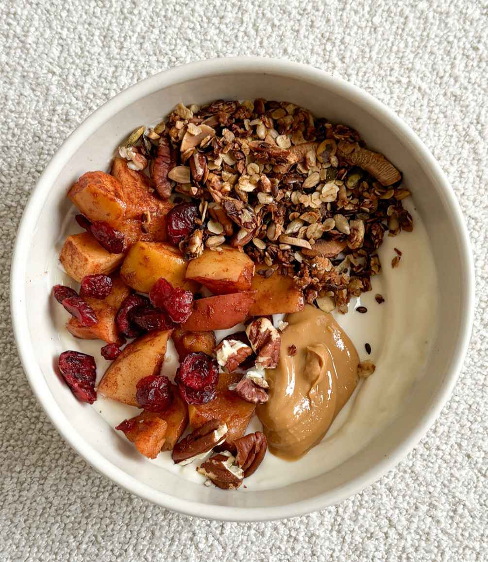 A healthy meal with yoghurt, nuts, fruit and peanut butter.